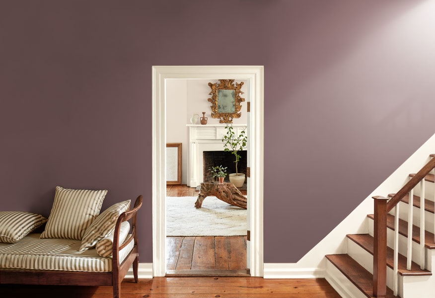 A hallway painted in Cinnamon Slate 2113-40 with woodwork painted in Glacier White OC-37, with a view through to a living room with walls painted in Sea Salt CSP-95.