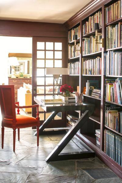 A library with painted bookcases and glazed double doors featuring Dinner Party AF-300. A vibrant burnt orange desk chair and dark brown desk complete the look