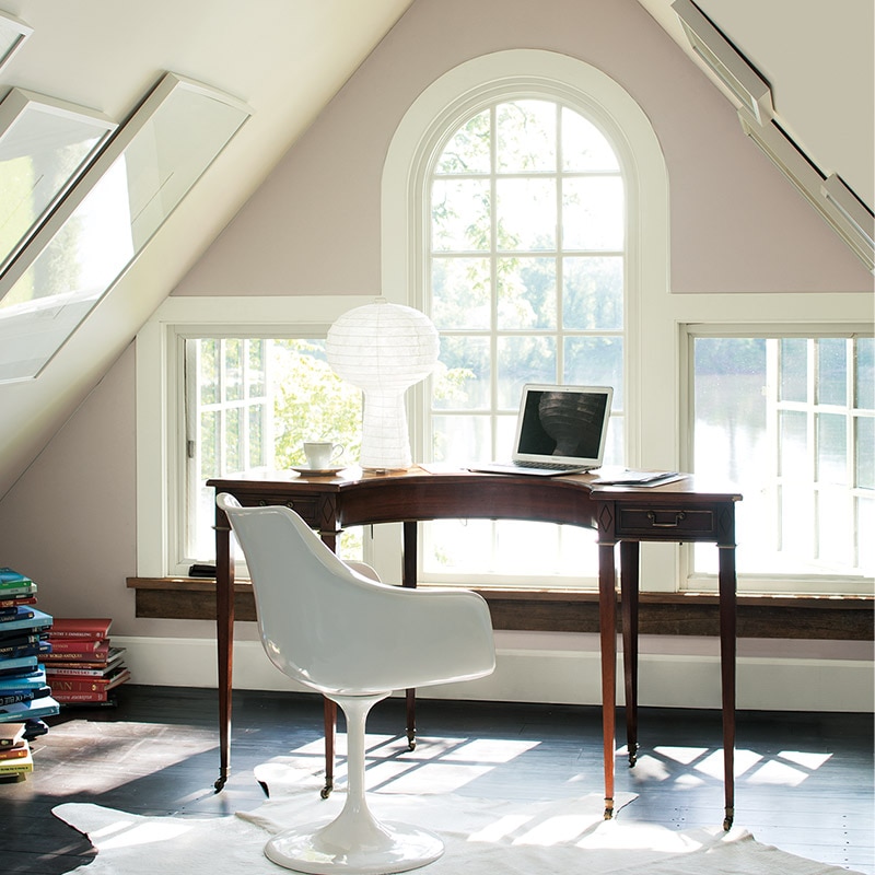 A curved desk in front of a gable end window. The walls are painted in Sandlot Gray 2107-50 and the sloping ceilings in Cloud Cover OC-25